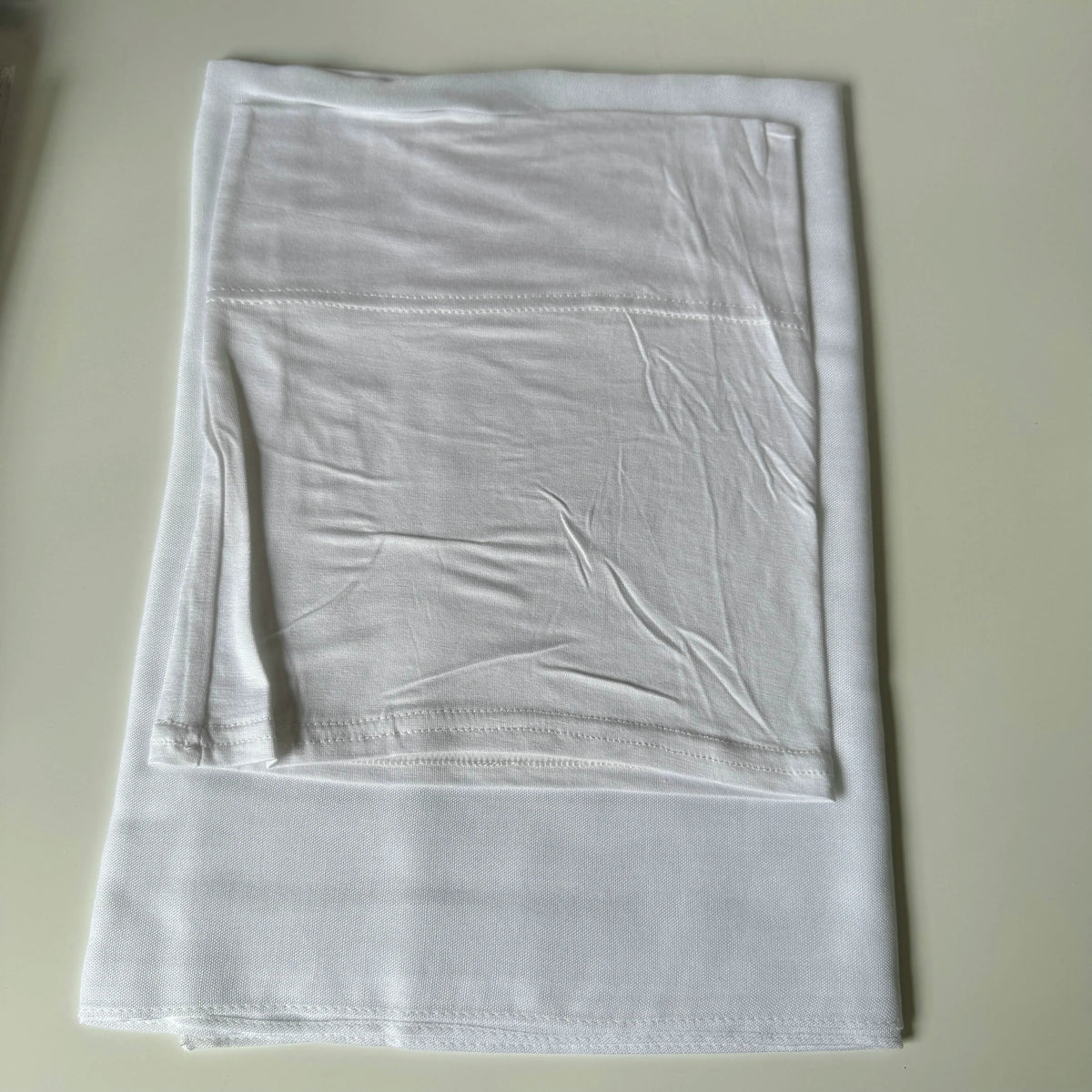 A white soft modal rayon hijab set folded neatly on a light surface.