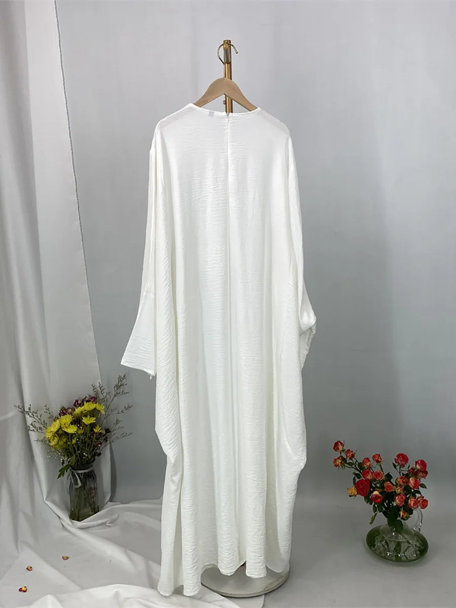 Elegante weiße Batwing-Abaya für Damen, präsentiert an einem Bügel vor hellem Hintergrund.