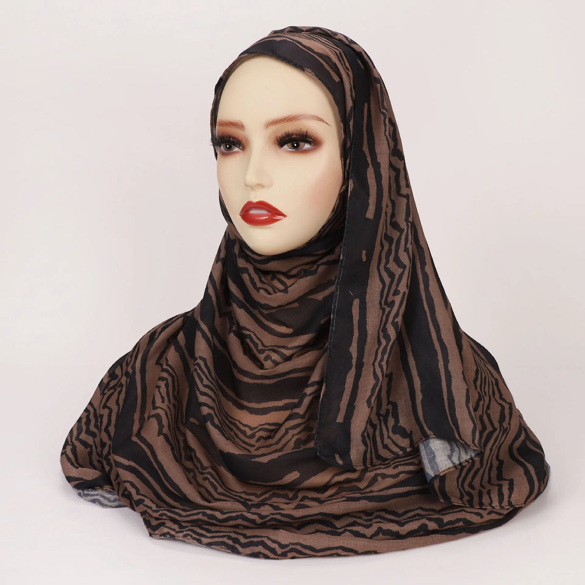 Cabeza de una mujer con un pañuelo hijab a rayas marrón y negro con estampado de leopardo.