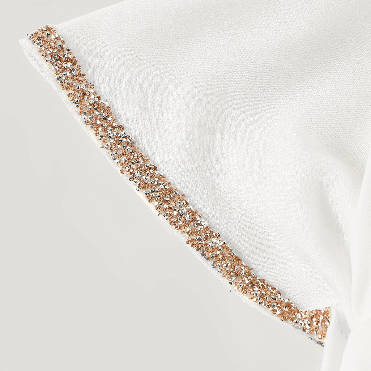 Gros plan d'un foulard modal blanc avec une délicate ligne de perles d'or et de diamants sur le bord.