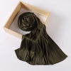 A dark olive green ribbed jersey hijab scarf is rolled and draped within a light wooden frame.