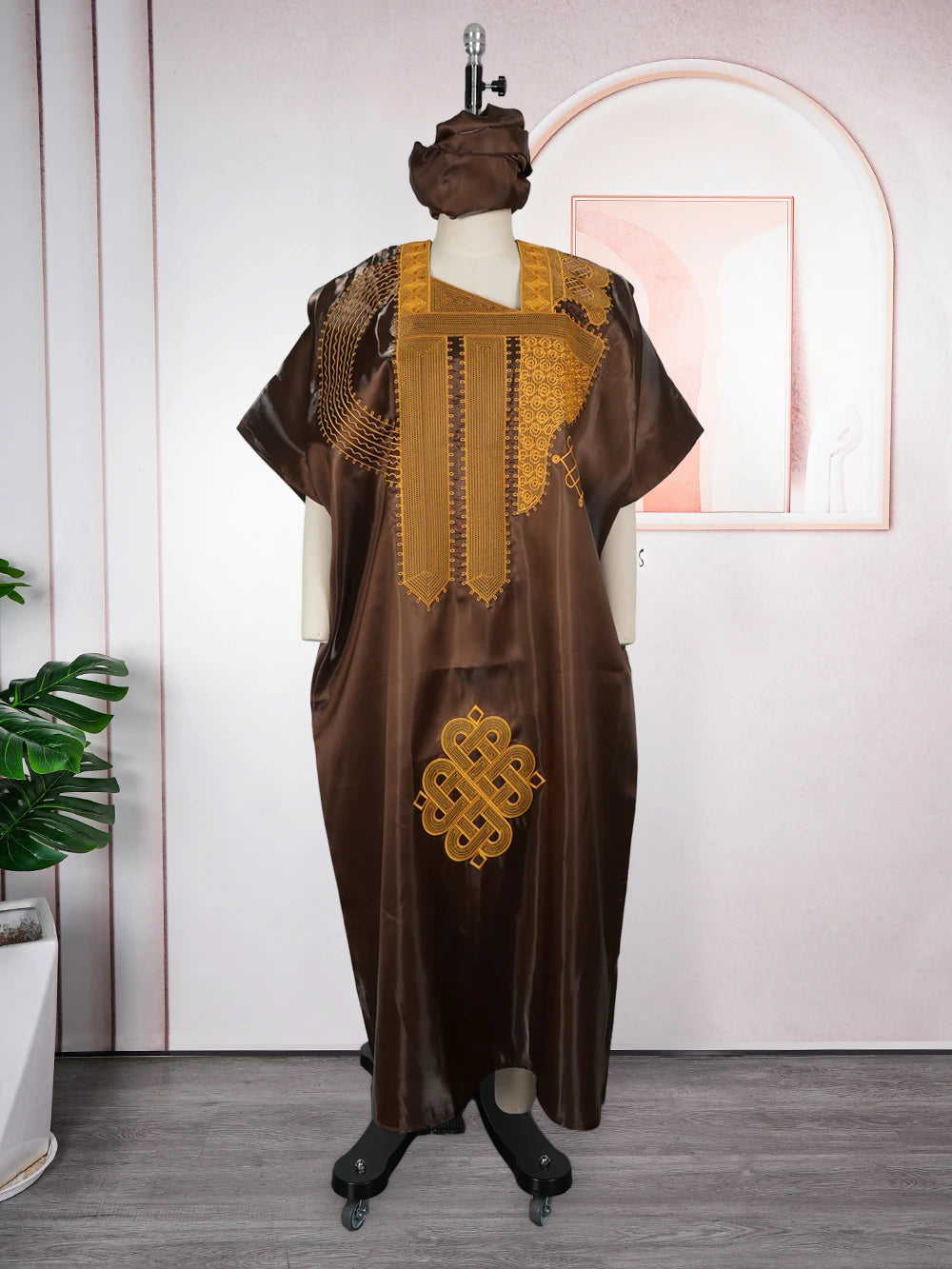 Dunkelbraunes traditionelles Ankara Dashiki-Kleid auf einem Mannequin vor pinker Wand.