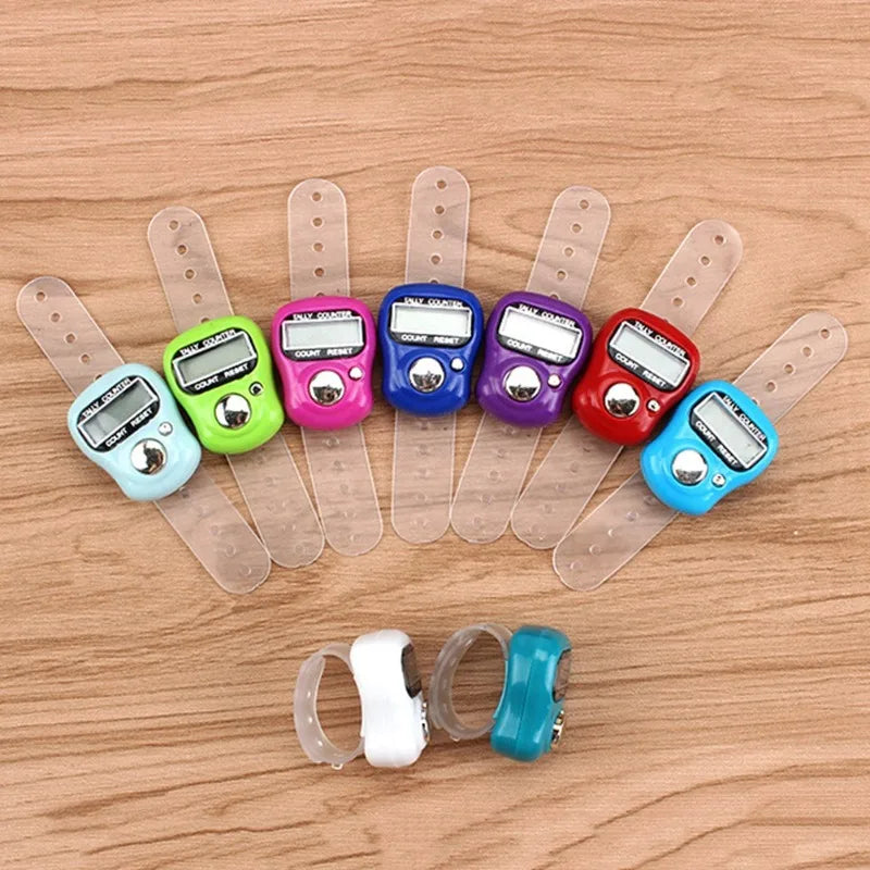 A collection of ten mini digital finger counters in various colors are displayed on a wooden surface.