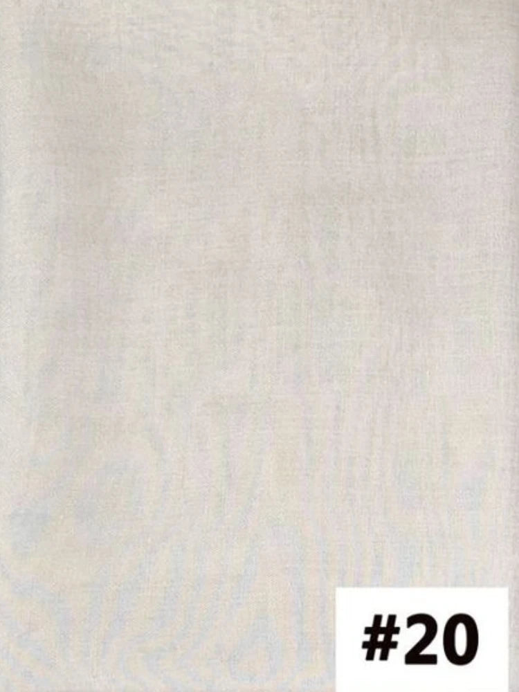 Un échantillon de tissu uni, beige clair ou blanc cassé, avec une texture visible.