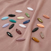 A collection of eight solid color brooch pins in various shades including white, green, blue, and peach, laid out on pink fab