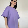 Una modelo vistiendo una camiseta básica de algodón oversize morada de verano y gafas de sol.