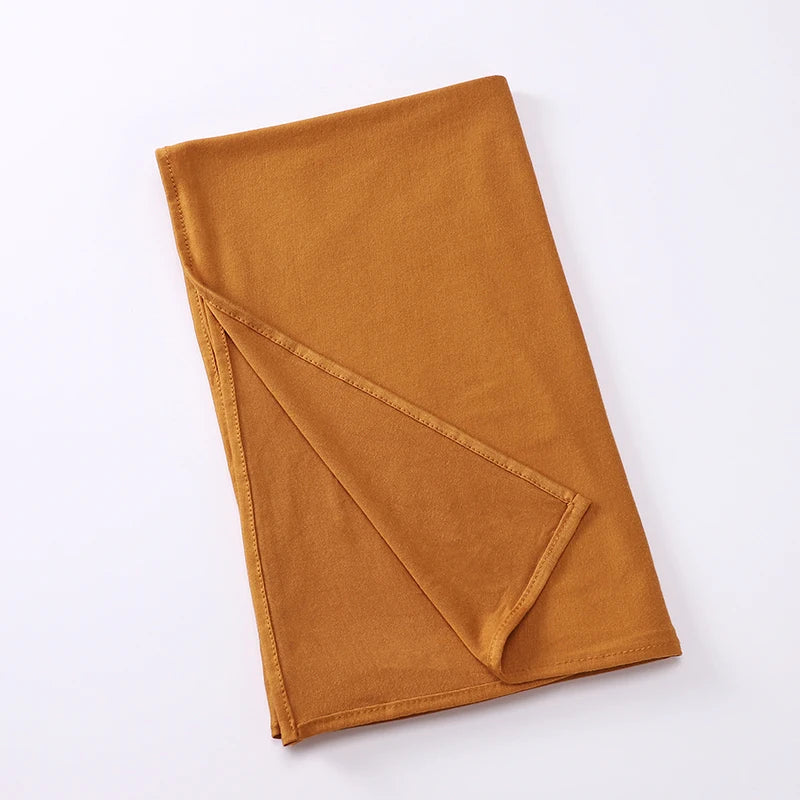 Écharpe instant hijab en jersey extensible orange brûlé, pliée, sur fond blanc.