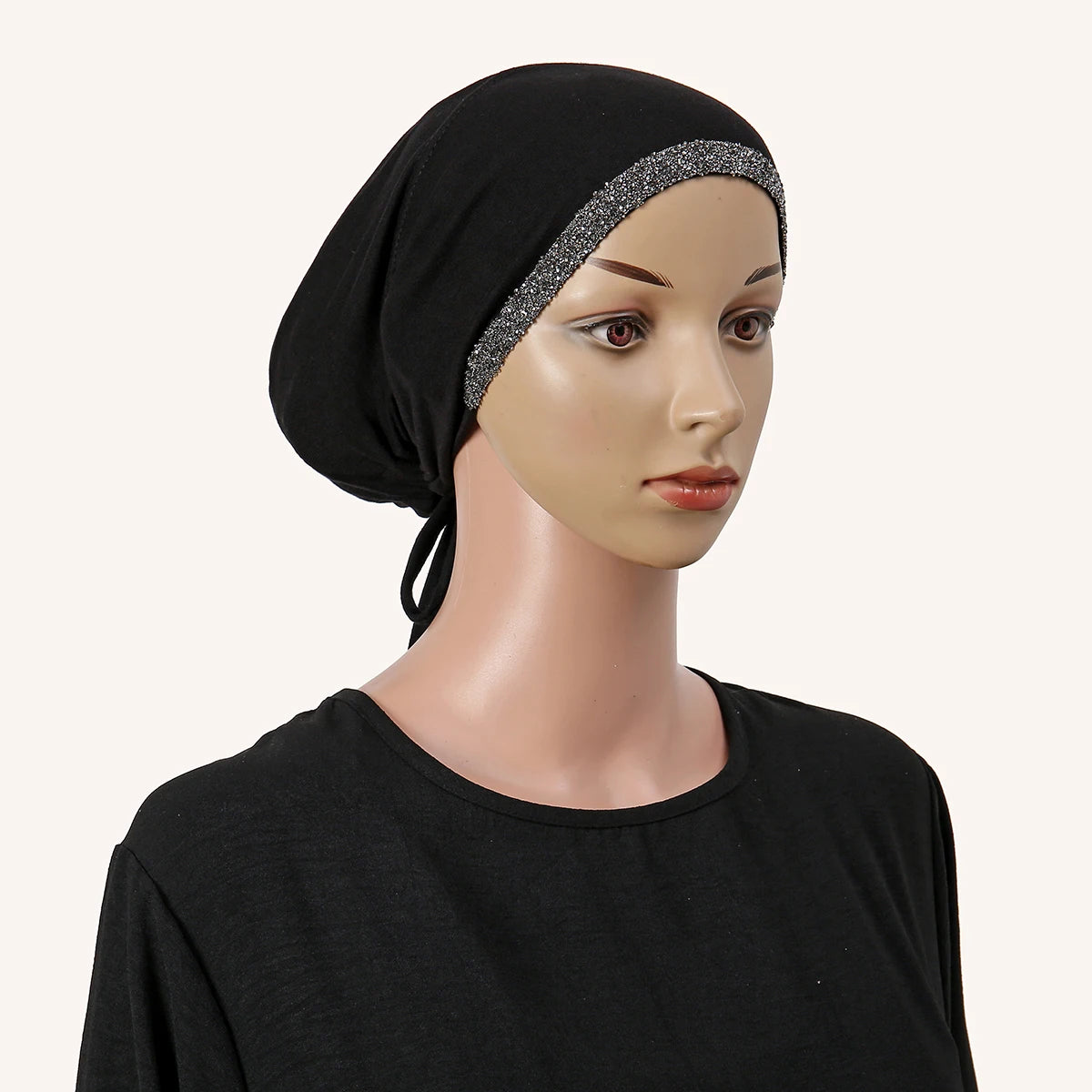 Eine Frau trägt ein schwarzes Hijab mit silbernem Strassrand und einem schwarzen Shirt.