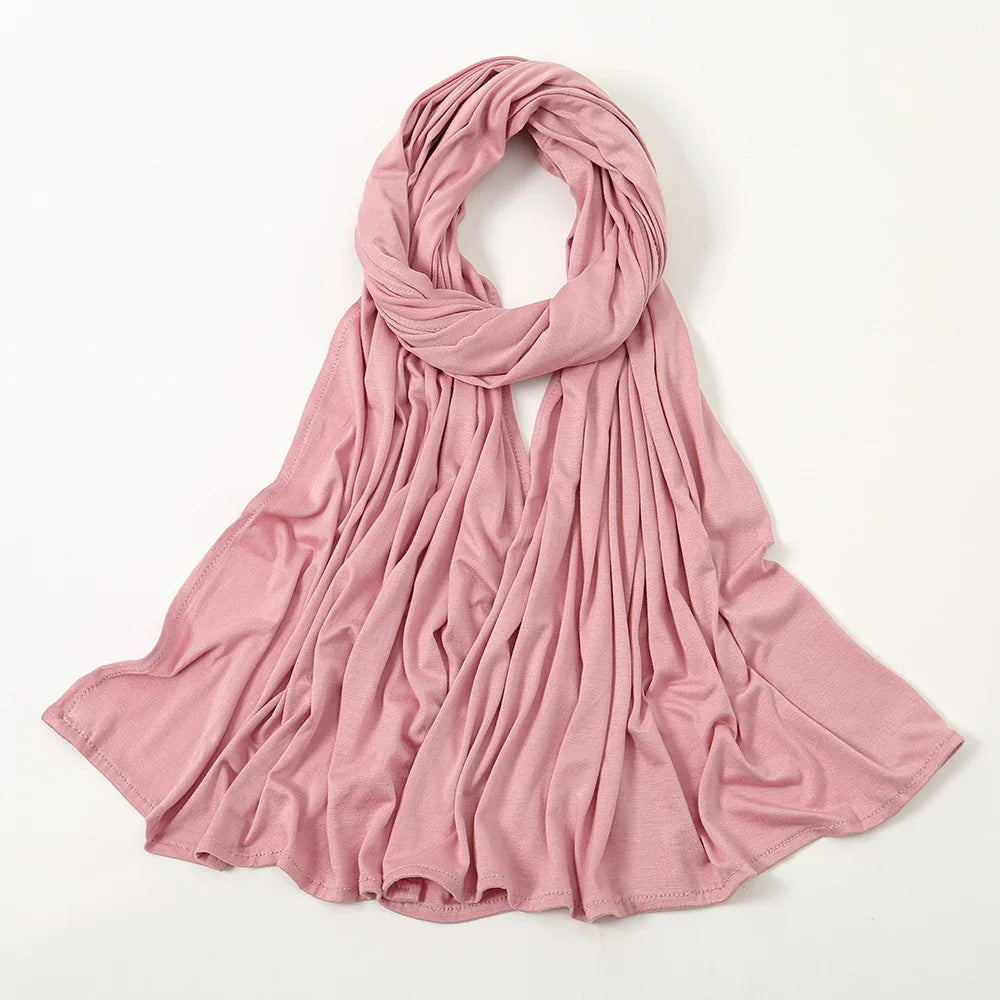 Weiches rosa Tuch/Schal, drapiert und gefaltet, auf weißem Hintergrund.