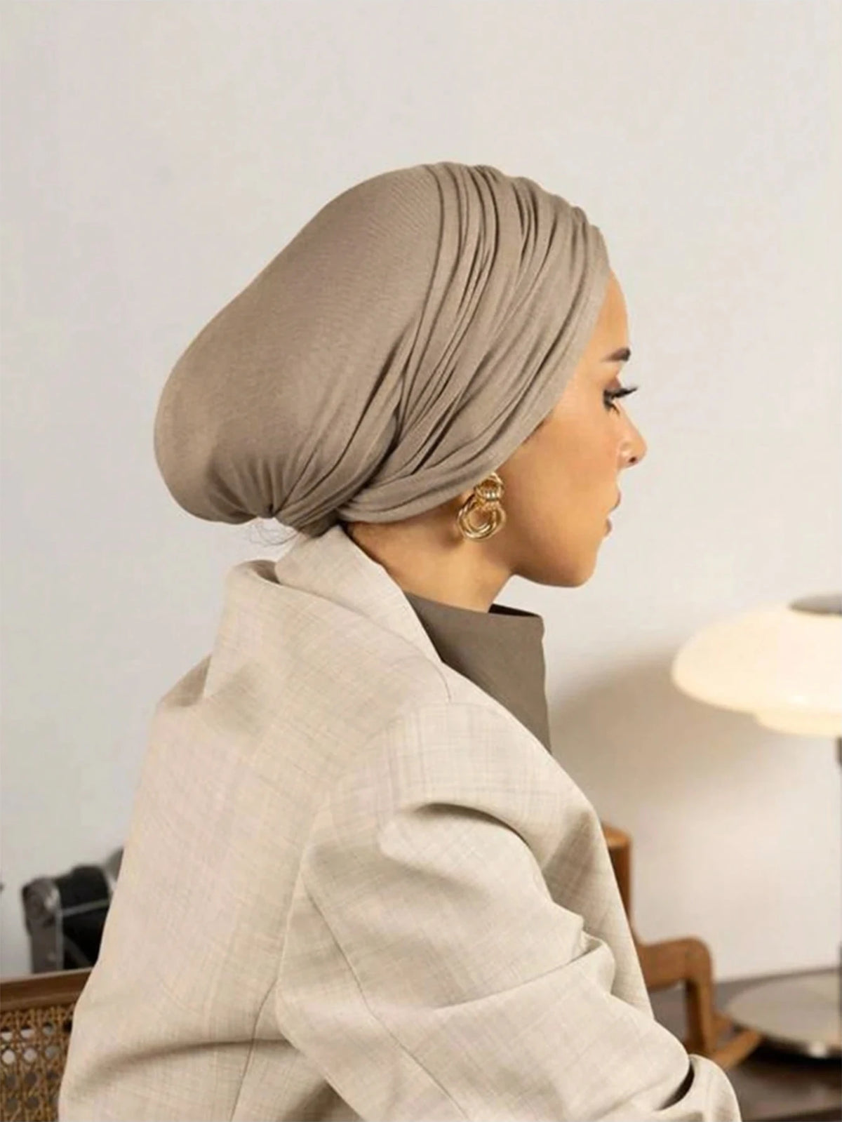 Femme portant un hijab beige instantané et un blazer beige clair, vue de profil.