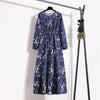 Marineblaue Boho-Blumenmuster-Maxikleid hängt an einem schwarzen Haken vor einer weißen Wand.