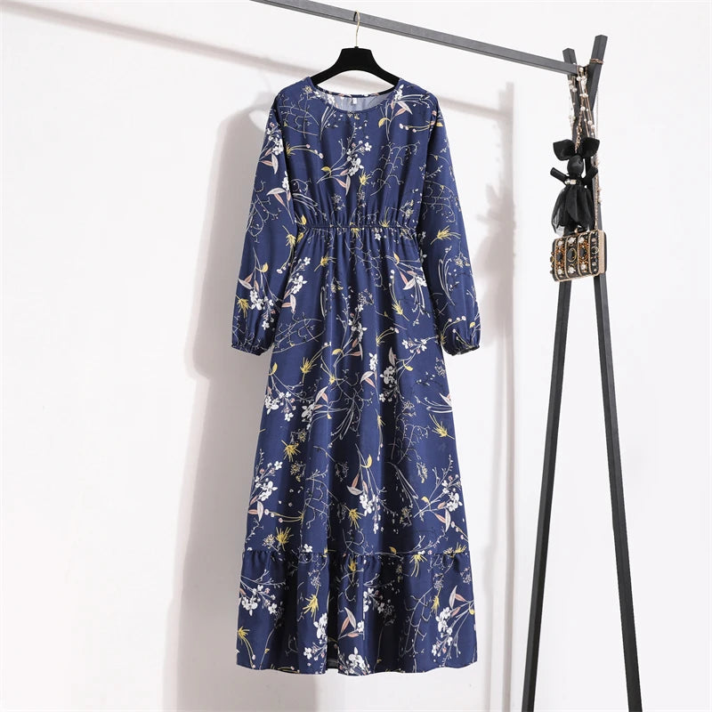 Marineblaue Boho-Blumenmuster-Maxikleid hängt an einem schwarzen Haken vor einer weißen Wand.