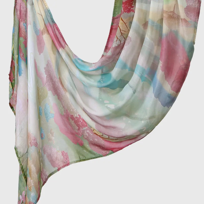 Elegant printed linen hijab scarf featuring soft pink, teal, and green watercolor floral patterns.