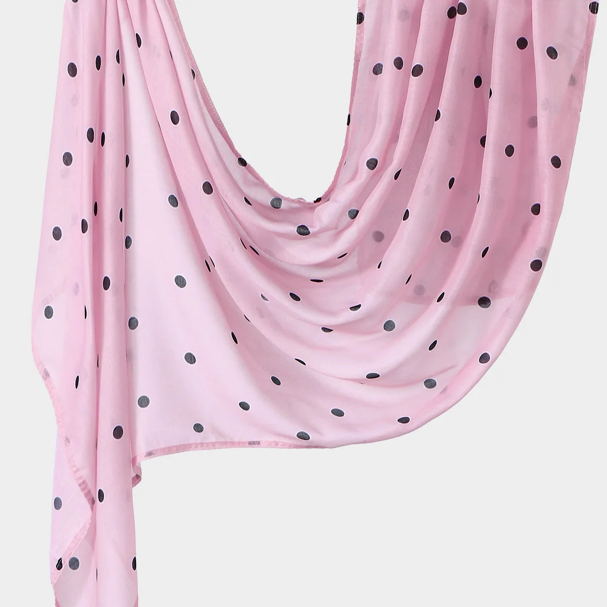 A pink linen hijab scarf with small dark polka dots draped elegantly.