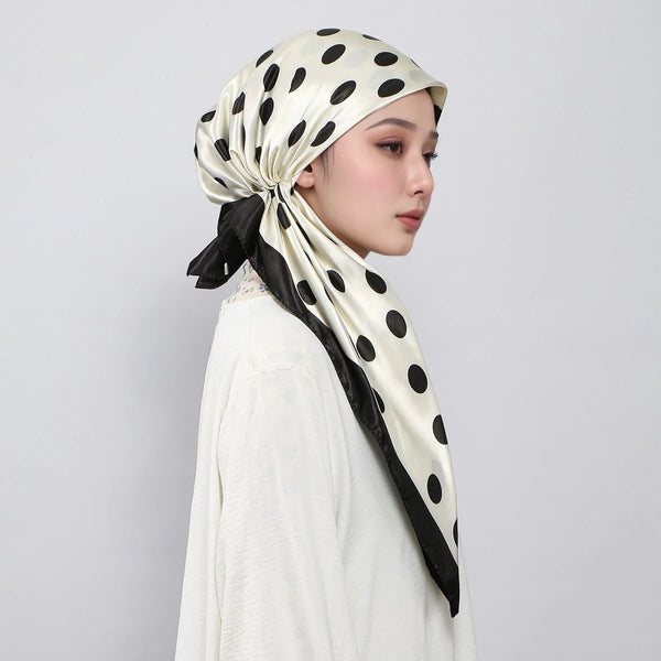A woman wearing a satin printed polka dot instant hijab scarf in beige and black on her head.