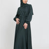 Eine Frau trägt eine dunkelgrüne marokkanische Kaftan-Abaya mit Kapuze und Gürtel.