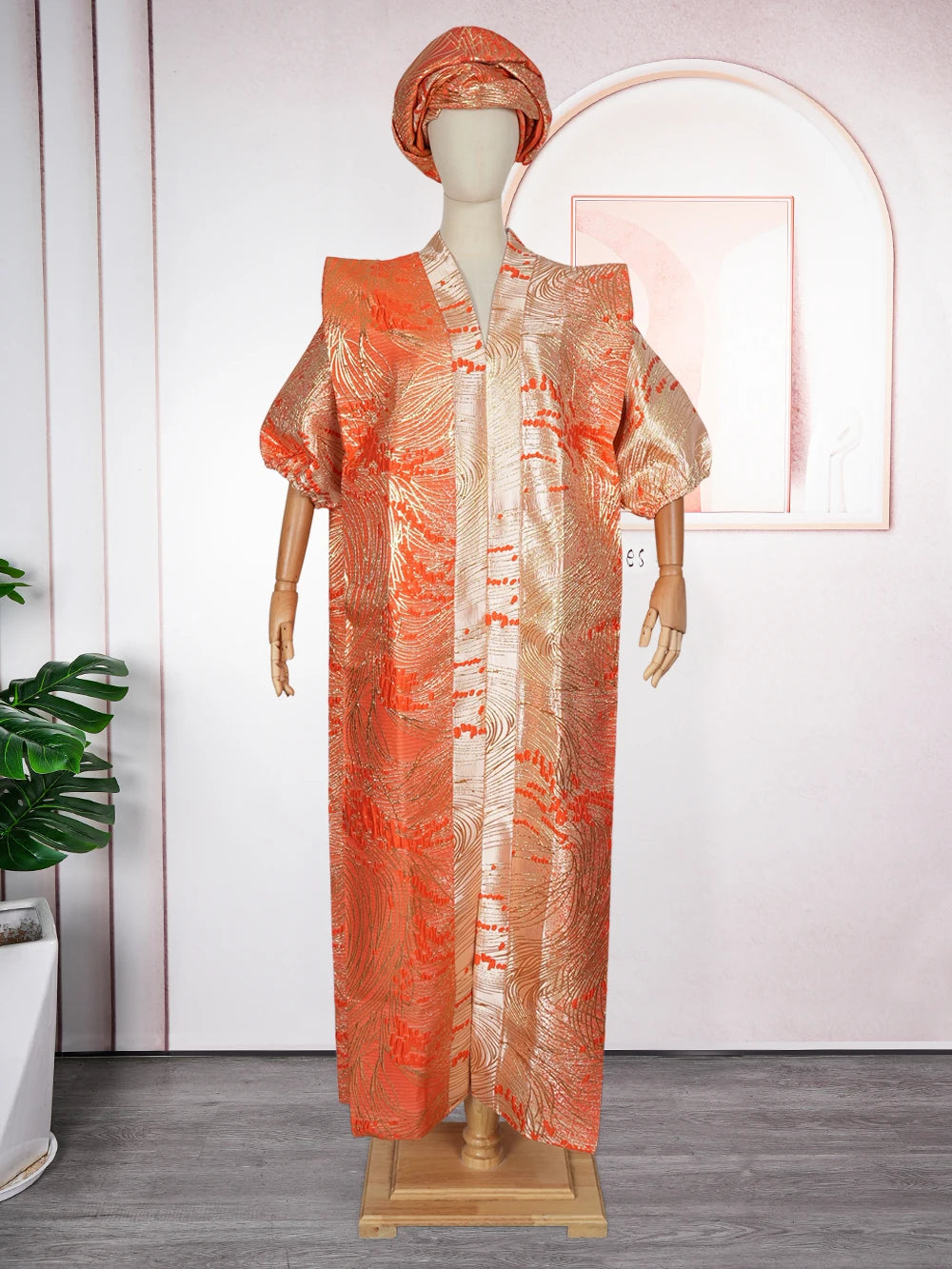 A woman wearing an orange satin abaya kaftan with intricate patterns, displayed on a mannequin.