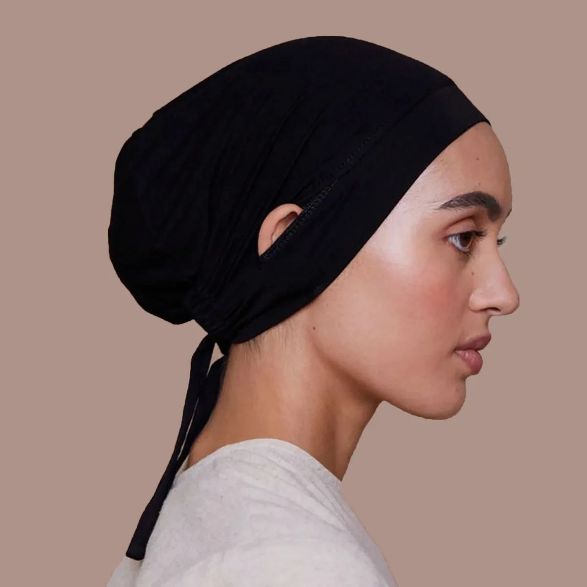 Gros plan du profil d'une femme portant un bonnet inner hijab noir à cordon.