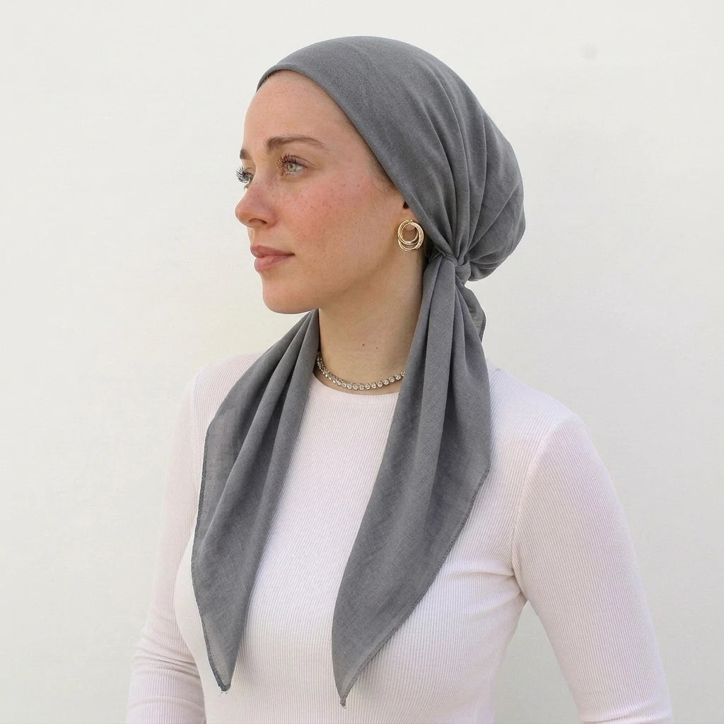 A woman wearing a solid gray linen elastic headscarf cap and a white top.