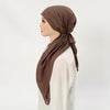 Une femme portant un hijab et un foulard en lin marron uni sur un haut blanc.