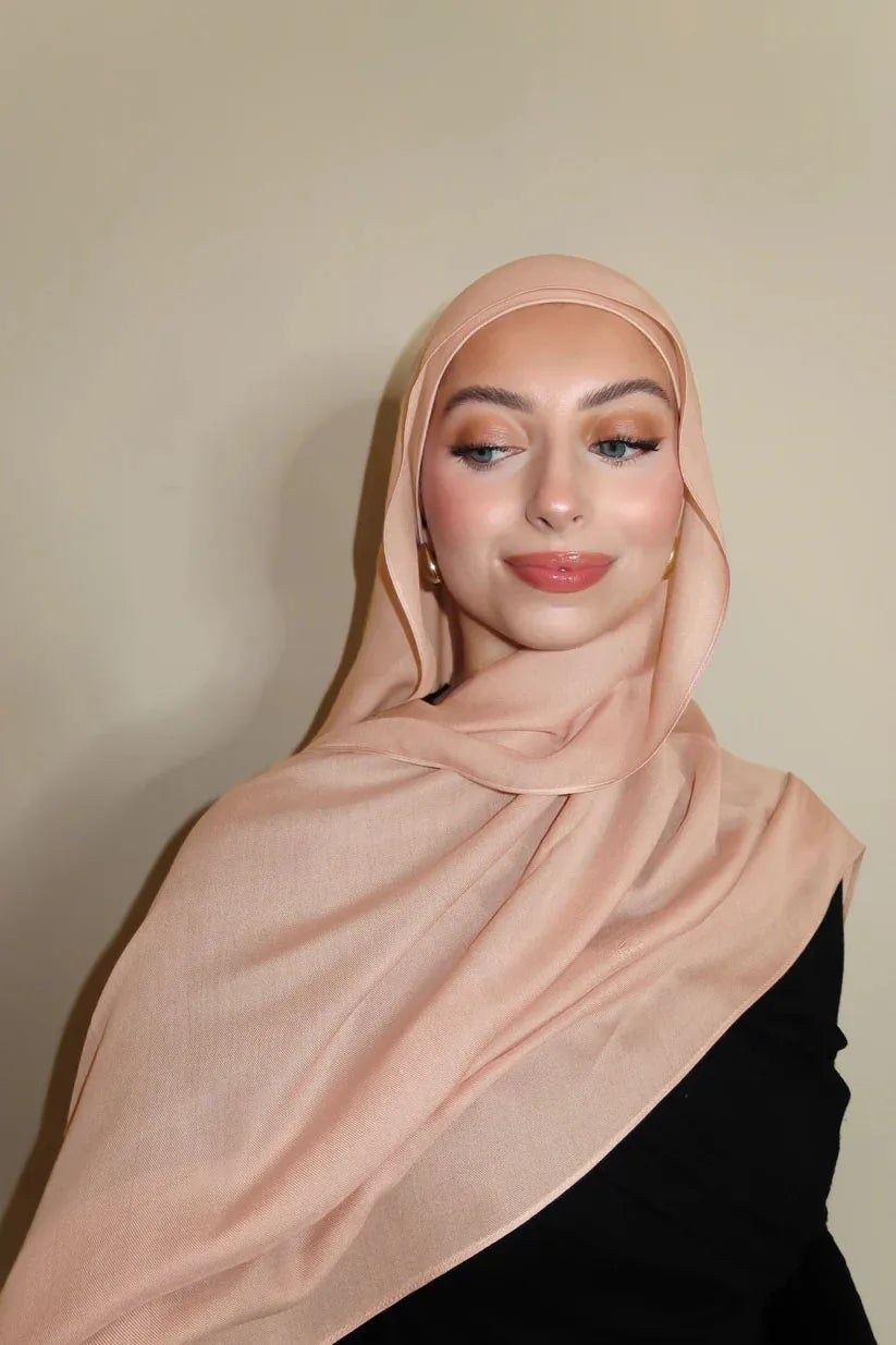 Eine Frau trägt einen weichen pinken Farbverlauf-Rayon-Modal-Hijab und schwarze Kleidung.