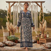 A model wears a long, dark blue bohemian floral maxi dress with lantern sleeves in an outdoor setting.