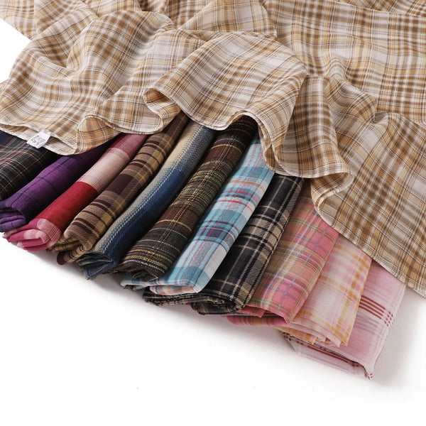 A stack of plaid print long chiffon hijab shawls in various muted colors and textures.