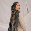 A woman wearing a brown and black plaid modal plaid hijab scarf over a beige top.