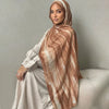 Una mujer vistiendo un pañuelo hijab de estampado acuarela marrón y un vestido gris claro.