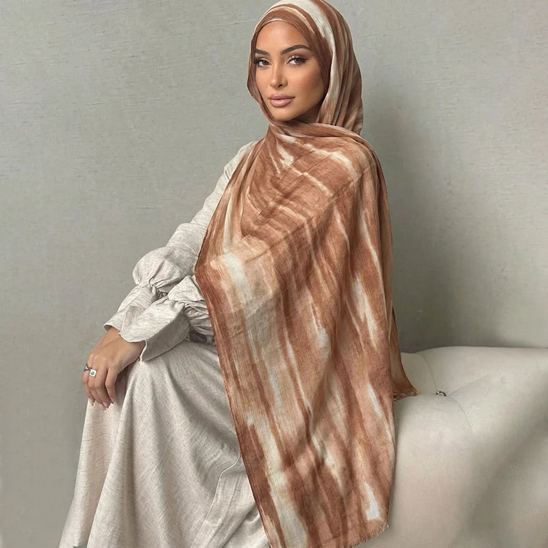Una mujer vistiendo un pañuelo hijab de estampado acuarela marrón y un vestido gris claro.
