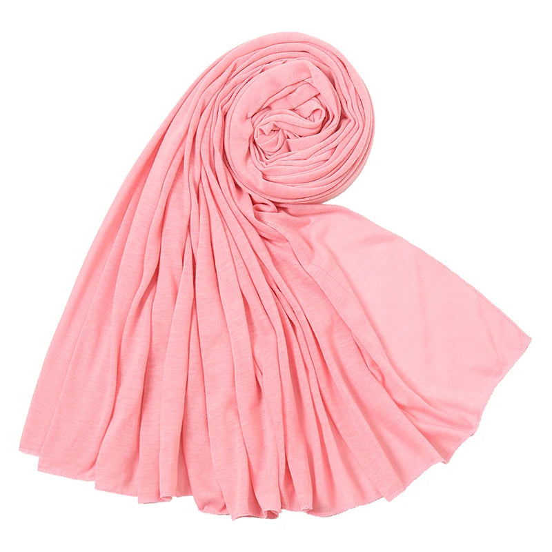Ein weicher rosa Baumwoll-Jersey-Hijabschal, gerollt und drapiert, zeigt seine fließende Textur.