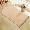 Alfombra de oración beige grabada con patrón geométrico y borlas decorativas doradas sobre suelo de madera clara.