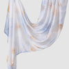 A flowing white linen hijab scarf with a soft blue floral print and gold accents.
