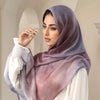 Eine Frau trägt einen lila bedruckten Baumwoll-Rayon-Hijabschal mit weißen Manschetten und einem weißen Oberteil.