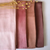 Vertikale Darstellung von Crinkle-Satin-Chiffon-Hijabstoff in Rosa-, Rosé- und Mauve-Tönen.