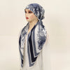 Une femme modélise un haut blanc et un foulard carré bleu et blanc à motif.
