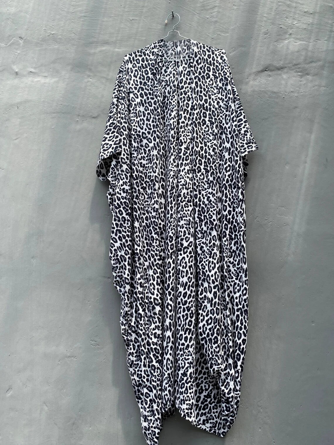 Schwarz-weißes Leopardenmuster Sommer-Strandkimono-Kleid hängt an einer grauen Wand.