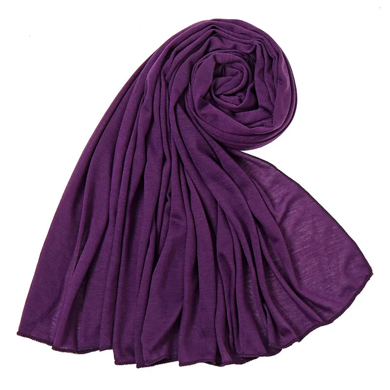 Un foulard hijab en jersey de coton violet profond, roulé et drapé, montrant sa texture douce.