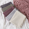 Una pila de pañuelos de jersey de algodón de hilo de varios colores en tonos malva, gris y beige.