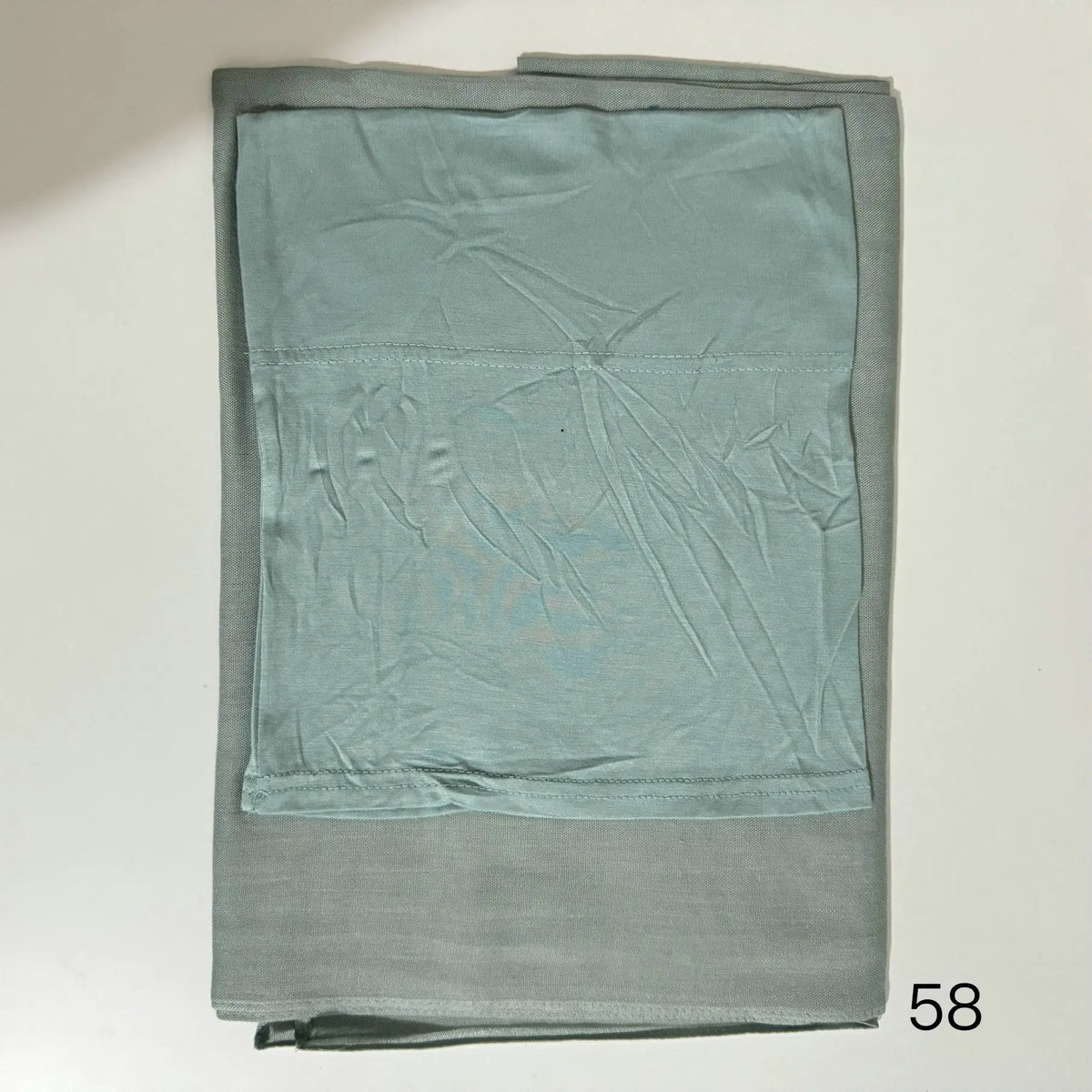 A folded soft teal hijab set made of modal rayon fabric.