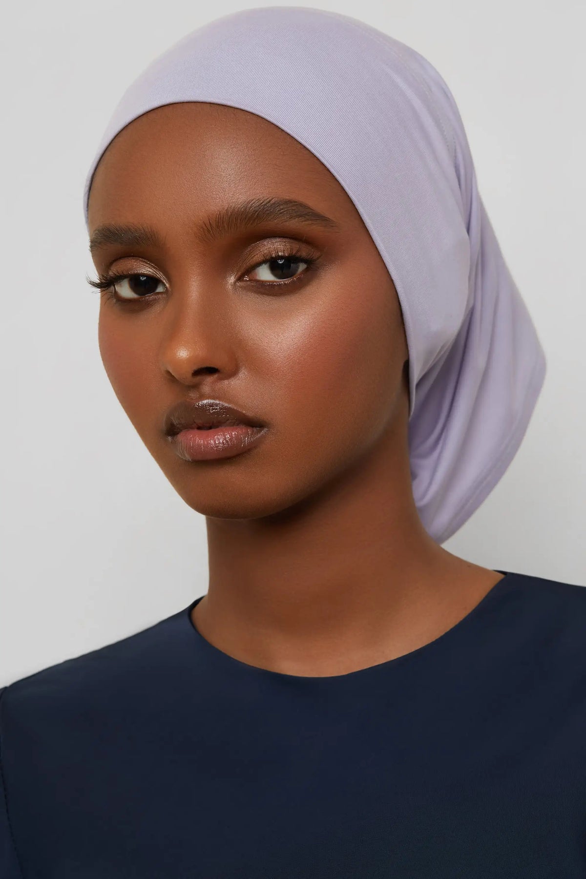 Model wearing a light purple bamboo jersey tube hijab cap and a dark blue top.