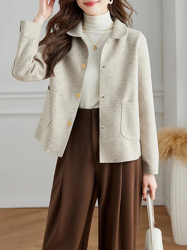 Une femme portant un manteau en laine beige sur un col roulé blanc et un pantalon marron.