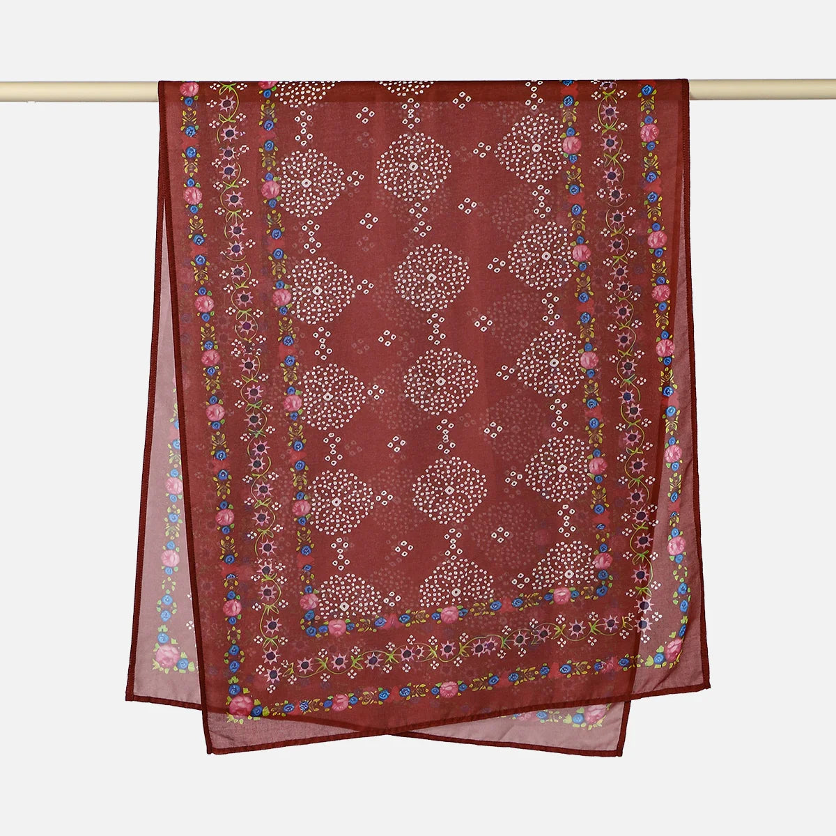 A maroon printed linen hijab scarf hanging on a rod.
