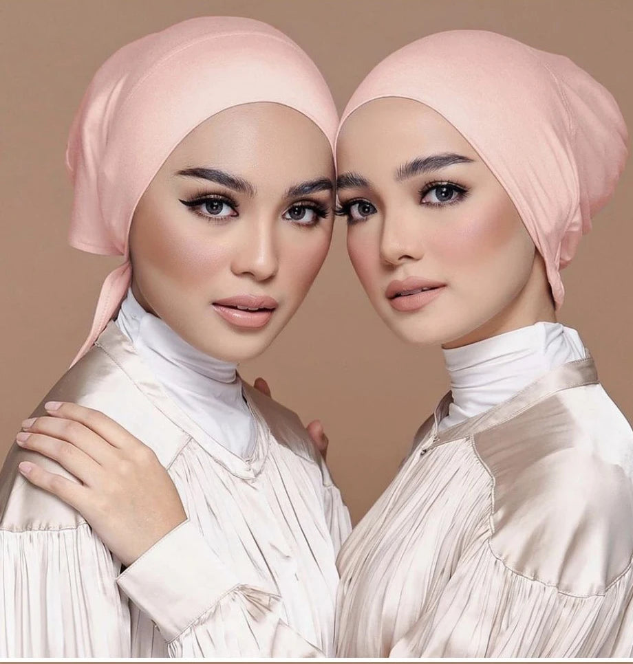 Dos mujeres vistiendo elegantes turbantes de modal rosa y tops de satén a juego