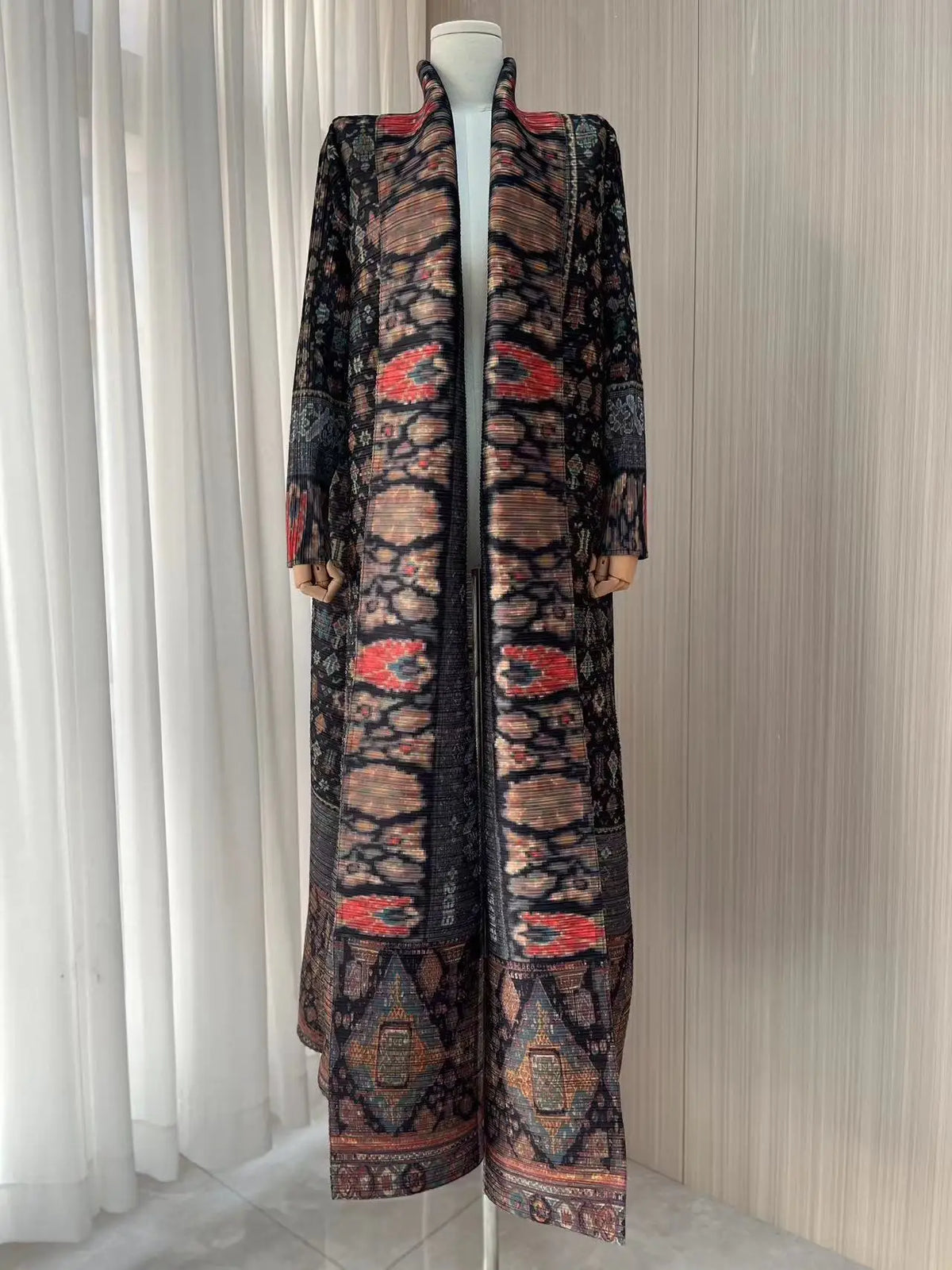 Manteau trench plissé long à motifs noirs et orange sur mannequin.