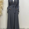 Eine Frau trägt ein langes, fließendes, dunkelgraues Abaya Kaftan mit offenem Front und gebundener Taille, kombiniert mit ein