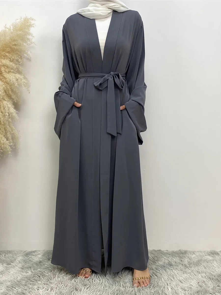 Eine Frau trägt ein langes, fließendes, dunkelgraues Abaya Kaftan mit offenem Front und gebundener Taille, kombiniert mit ein
