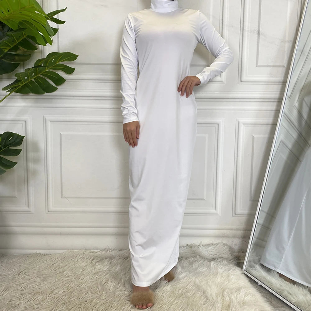 Ein langes, weißes Abaya-Kleid mit Langarm und Rollkragen, getragen von einem Model in Innenraum.