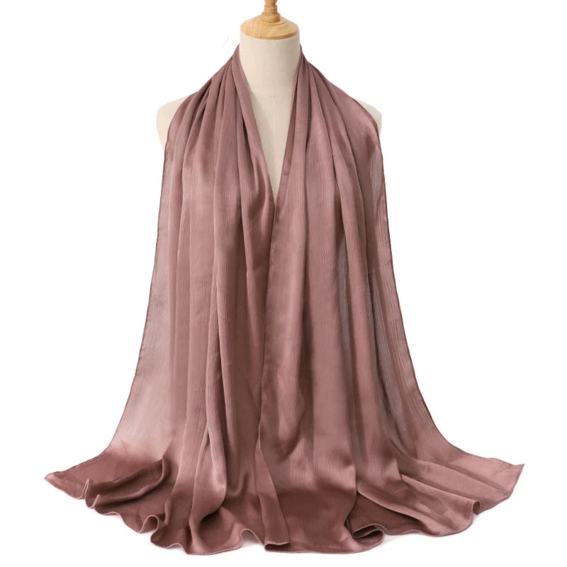 Ein drapierter, staubrosa satinierter Crinkle-Hijab-Schal auf einem Mannequin.
