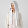 Une femme portant un foulard triangle élégant blanc et un haut rose pâle.